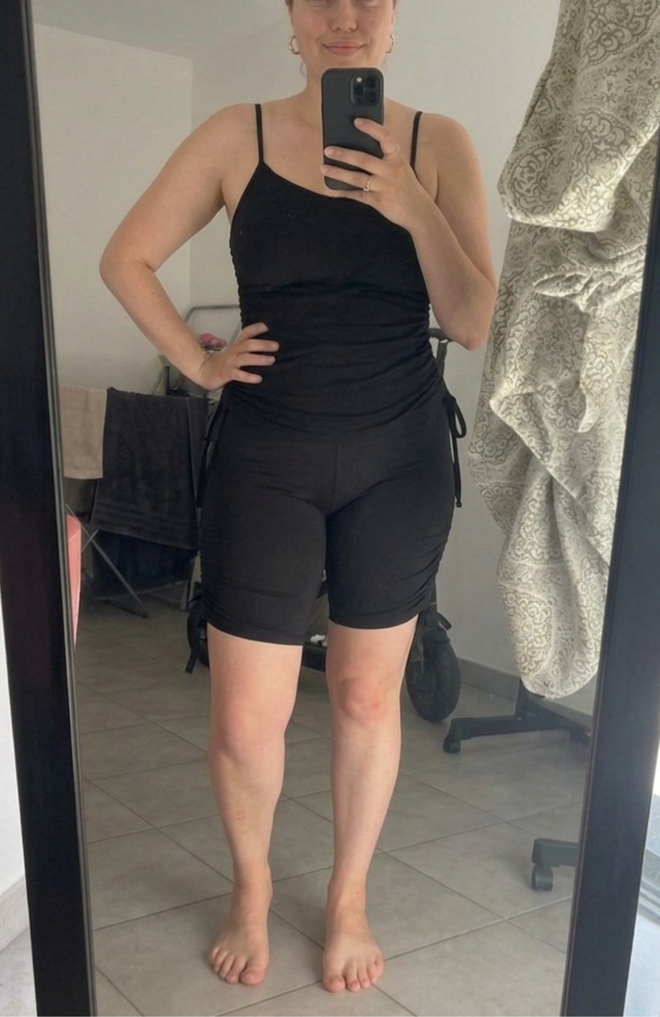 Une femme de grande taille se prenant en photo devant un miroir avec son ensemble de bain semi-couvrant Eclypse. Le top et le short s'adaptent à sa morphologie pour un confort total sans complexe. Image